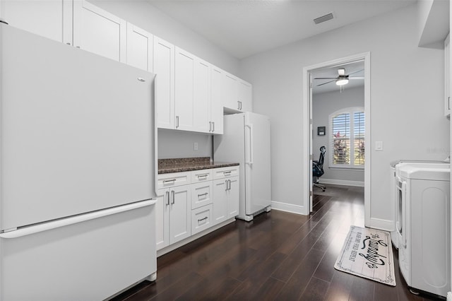 kitchen with washing machine and dryer, white fridge, white cabinetry, and dark hardwood / wood-style floors