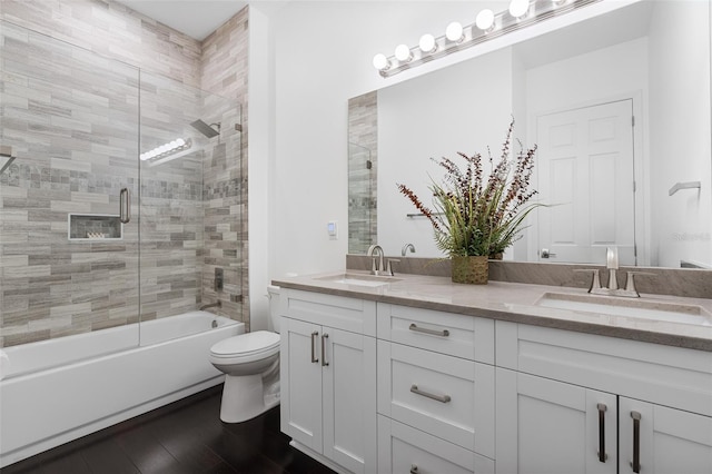 full bathroom with toilet, vanity, hardwood / wood-style floors, and combined bath / shower with glass door