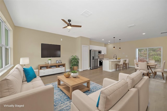 living room with sink, ceiling fan, and light hardwood / wood-style flooring