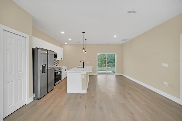 kitchen featuring sink, an island with sink, pendant lighting, stainless steel appliances, and white cabinets