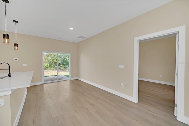 unfurnished living room with sink and light hardwood / wood-style flooring