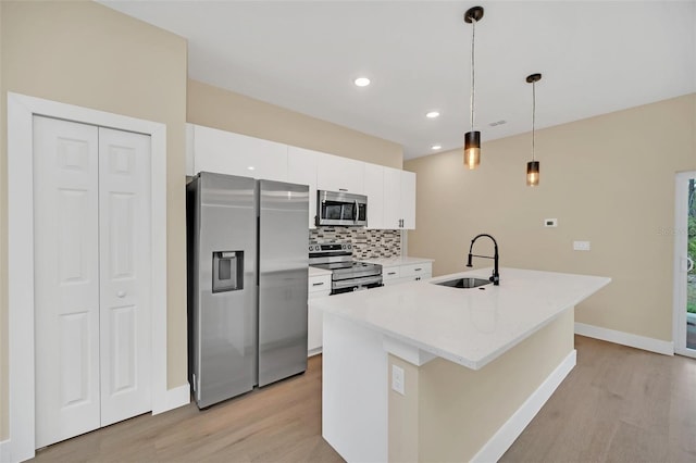 kitchen featuring appliances with stainless steel finishes, decorative light fixtures, white cabinetry, an island with sink, and sink