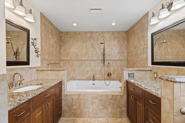 bathroom featuring vanity, a relaxing tiled tub, and tile walls