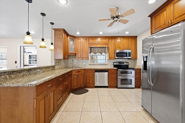 kitchen with kitchen peninsula, appliances with stainless steel finishes, light stone countertops, sink, and hanging light fixtures