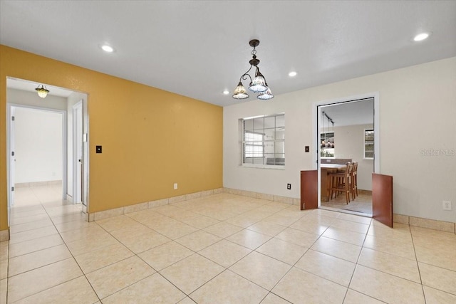 tiled empty room featuring a chandelier