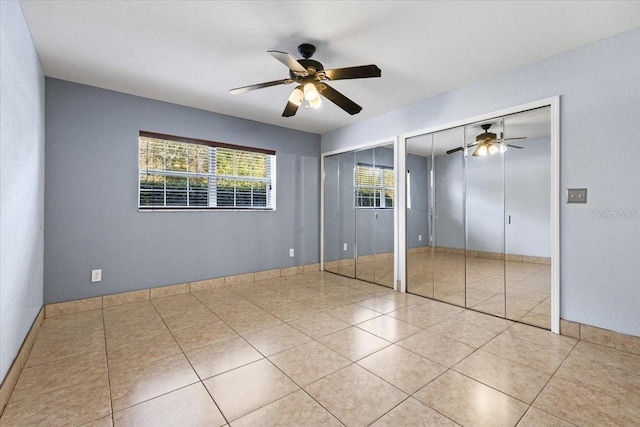 unfurnished bedroom featuring light tile patterned floors, two closets, and ceiling fan