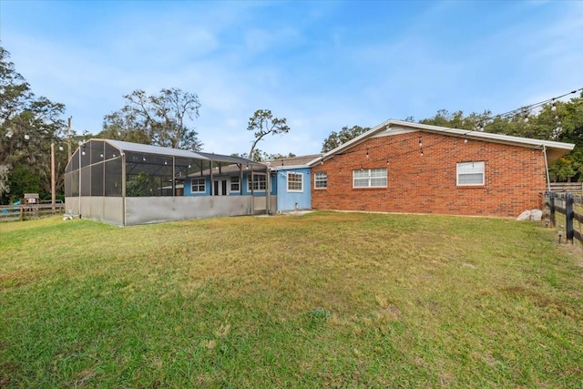 rear view of property featuring a lanai and a lawn