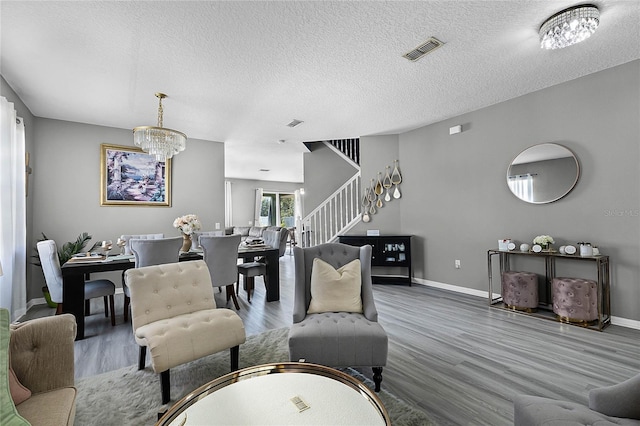 living room featuring hardwood / wood-style floors, a textured ceiling, and an inviting chandelier