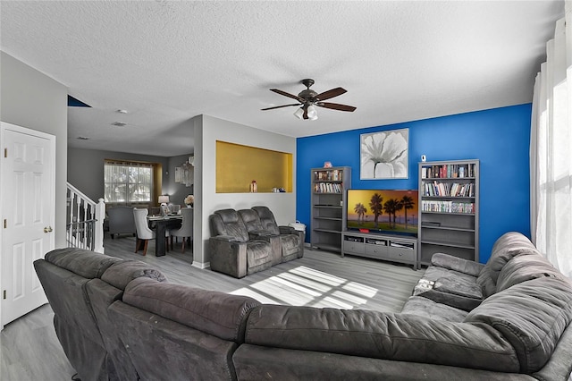 living room featuring hardwood / wood-style floors, ceiling fan, and a textured ceiling