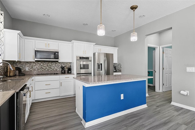 kitchen featuring sink, decorative light fixtures, a kitchen island, white cabinetry, and stainless steel appliances