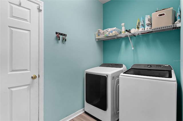 laundry room with washing machine and dryer and light hardwood / wood-style floors