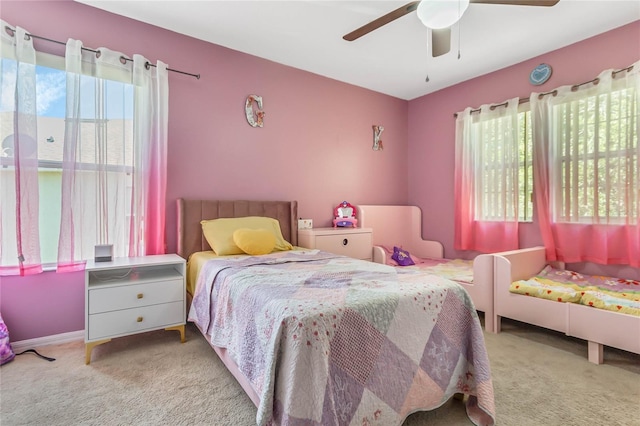 bedroom with ceiling fan, light carpet, and multiple windows