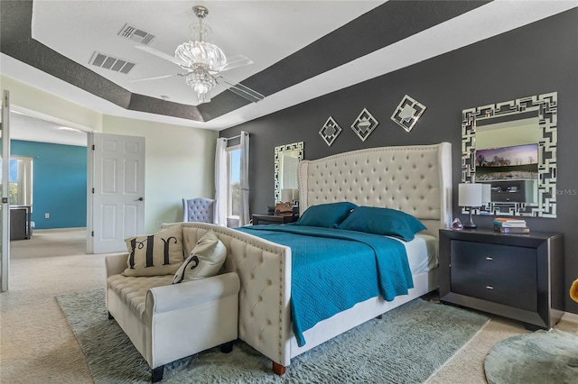 bedroom with carpet floors, a raised ceiling, multiple windows, and ceiling fan