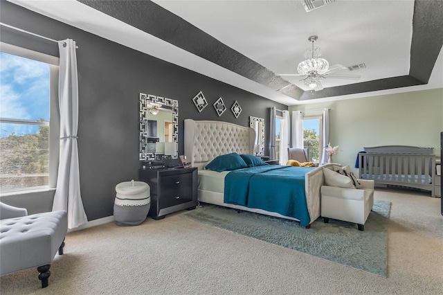 carpeted bedroom featuring a raised ceiling and ceiling fan