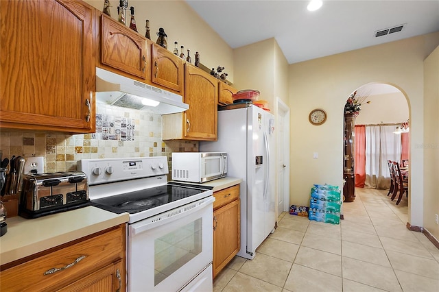 kitchen featuring tasteful backsplash, light tile patterned floors, and white appliances