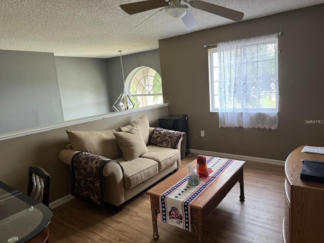 living room featuring wood-type flooring, a textured ceiling, and ceiling fan