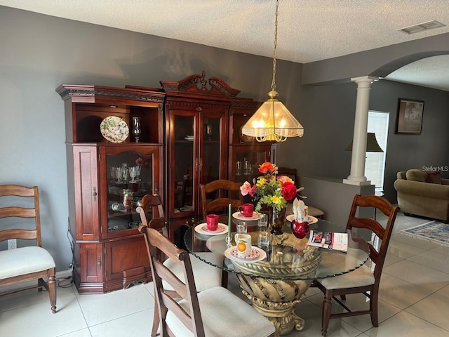 tiled dining area with a textured ceiling and decorative columns