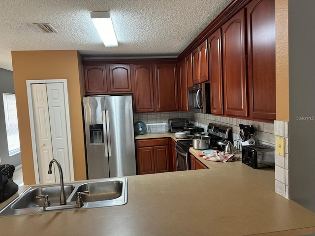 kitchen featuring kitchen peninsula, stainless steel appliances, tasteful backsplash, and sink