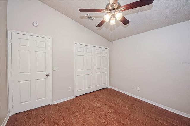 unfurnished bedroom featuring vaulted ceiling, hardwood / wood-style flooring, ceiling fan, a textured ceiling, and a closet