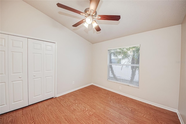 unfurnished bedroom with vaulted ceiling, ceiling fan, light wood-type flooring, and a closet