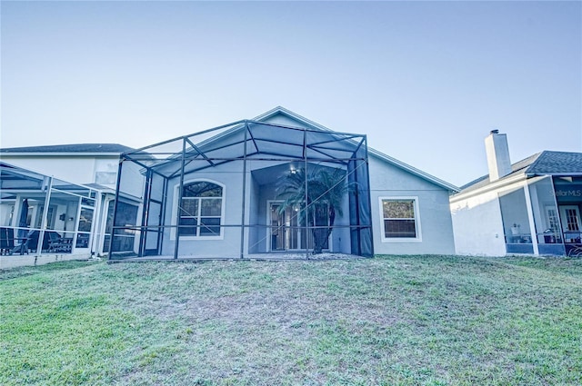 rear view of property featuring a lanai and a lawn