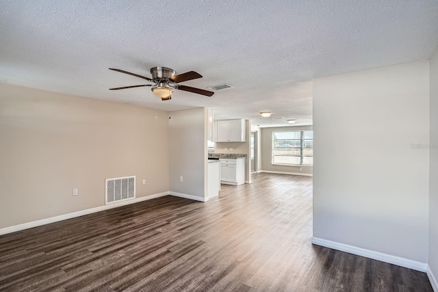 unfurnished living room featuring ceiling fan, dark hardwood / wood-style floors, and a textured ceiling