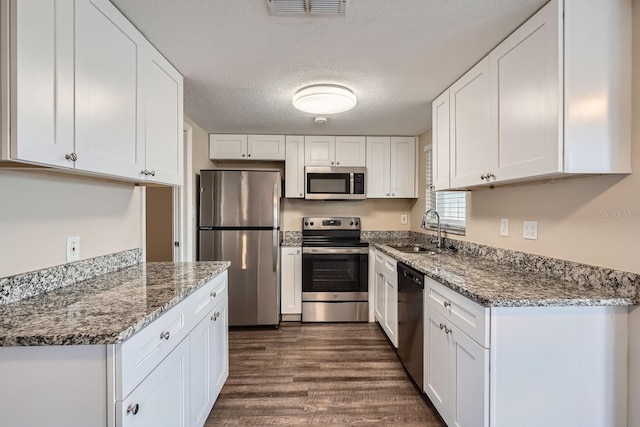 kitchen featuring stone counters, sink, stainless steel appliances, a textured ceiling, and white cabinets