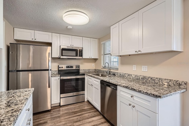 kitchen with white cabinetry, sink, dark wood-type flooring, stainless steel appliances, and a textured ceiling