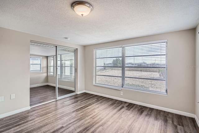 unfurnished room with hardwood / wood-style floors, a textured ceiling, and a wealth of natural light