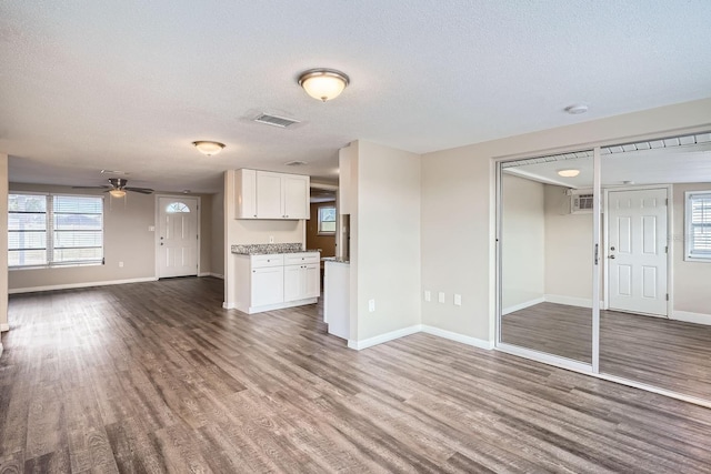 unfurnished living room with hardwood / wood-style floors, a textured ceiling, and ceiling fan