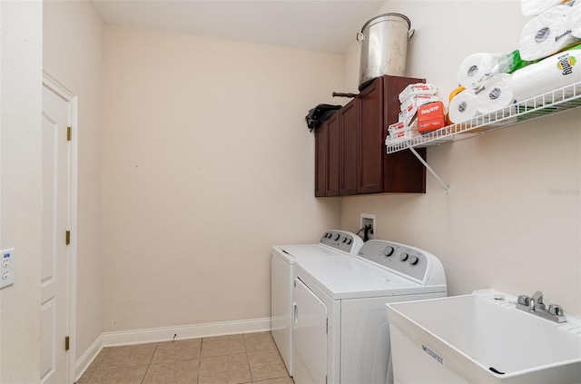 laundry area with washing machine and dryer, sink, light tile patterned floors, and cabinets