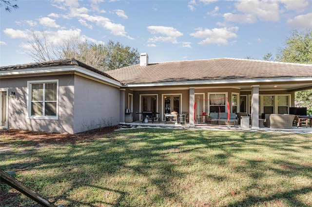 rear view of property featuring a lawn and a patio area