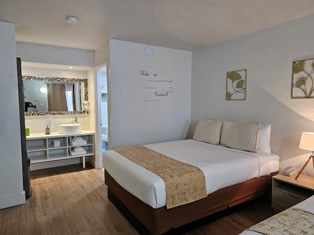 bedroom featuring hardwood / wood-style floors, a textured ceiling, and connected bathroom