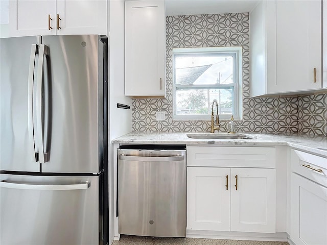 kitchen featuring light stone countertops, backsplash, stainless steel appliances, sink, and white cabinetry