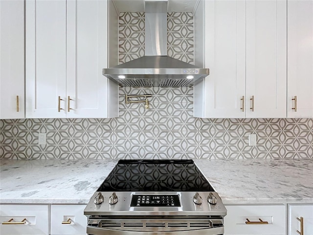 kitchen featuring white cabinetry, decorative backsplash, wall chimney exhaust hood, and stainless steel stove