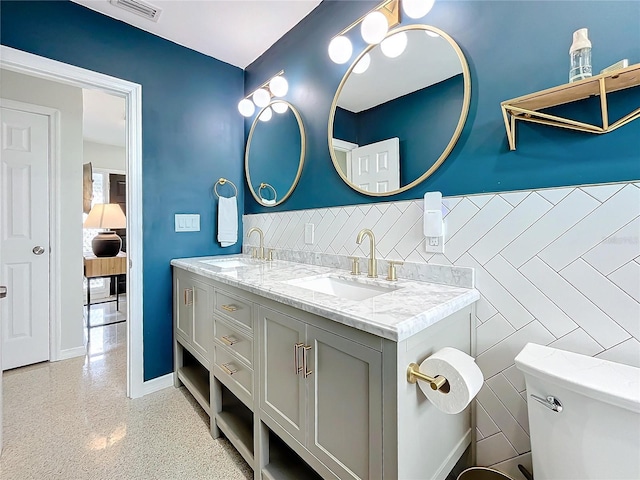 bathroom featuring vanity, toilet, and tile walls