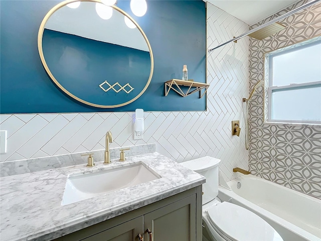 full bathroom featuring tiled shower / bath combo, toilet, tile walls, and vanity