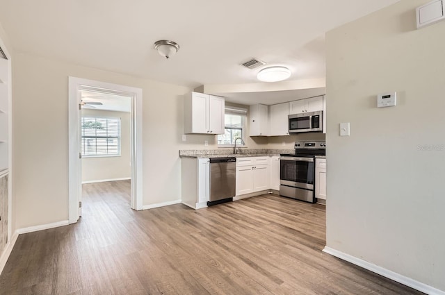 kitchen with white cabinets, appliances with stainless steel finishes, and plenty of natural light