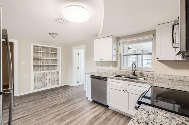 kitchen with light hardwood / wood-style floors, white cabinets, sink, stainless steel appliances, and light stone counters