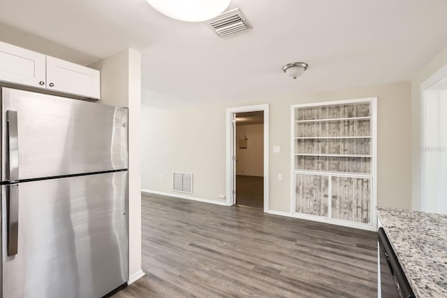 kitchen featuring light stone countertops, white cabinetry, built in shelves, dark hardwood / wood-style floors, and stainless steel fridge