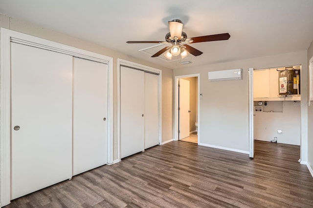 unfurnished bedroom featuring multiple closets, ceiling fan, water heater, dark hardwood / wood-style floors, and an AC wall unit