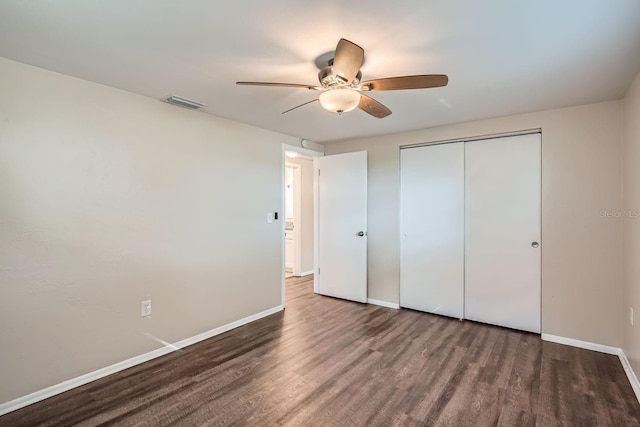 unfurnished bedroom featuring dark hardwood / wood-style flooring, ceiling fan, and a closet