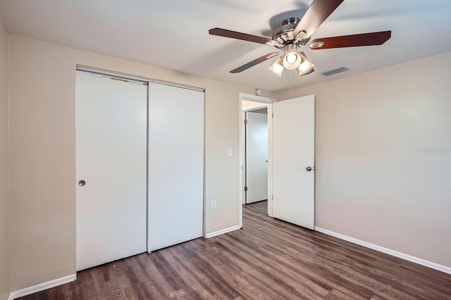 unfurnished bedroom featuring ceiling fan, a closet, and dark wood-type flooring