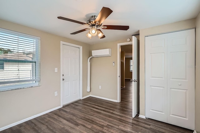 unfurnished bedroom featuring dark hardwood / wood-style floors, a wall unit AC, and ceiling fan