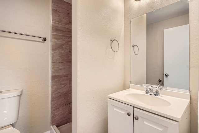 bathroom featuring a shower, vanity, and toilet