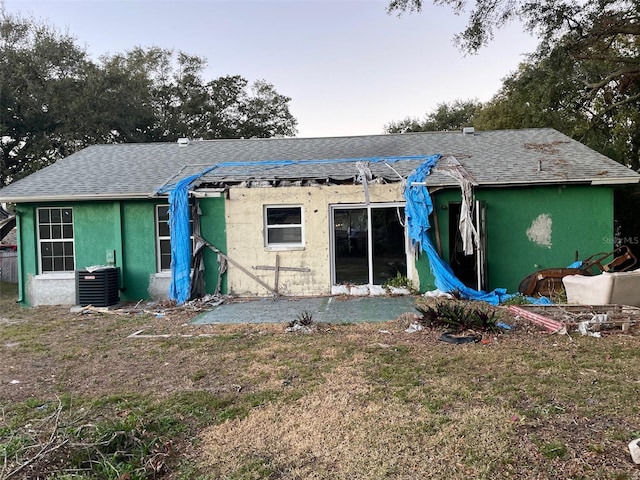 rear view of house with cooling unit and a lawn