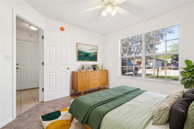 carpeted bedroom with ceiling fan and tile patterned flooring