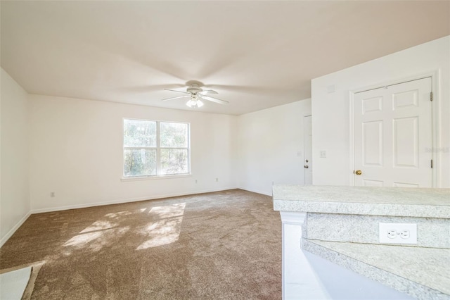 interior space with carpet flooring, a ceiling fan, and baseboards