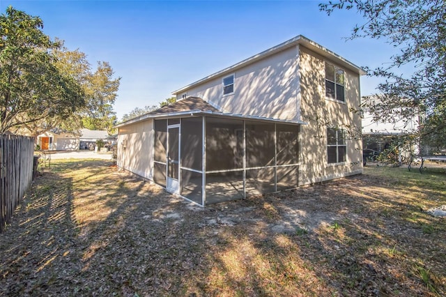 back of property with fence and a sunroom