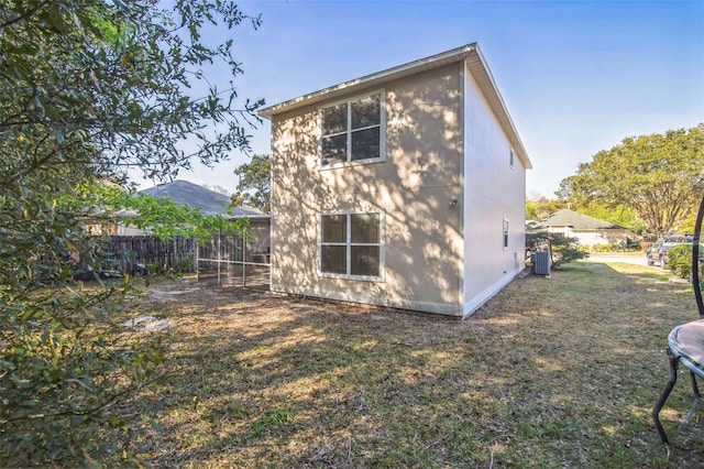 back of property with cooling unit, fence, a trampoline, and a lawn